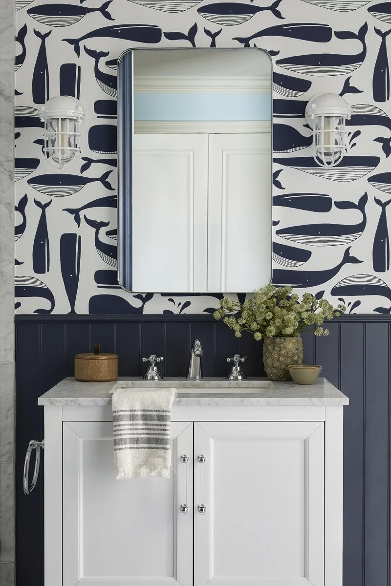 bathroom with whale print wallpaper, navy panelling and white vanity