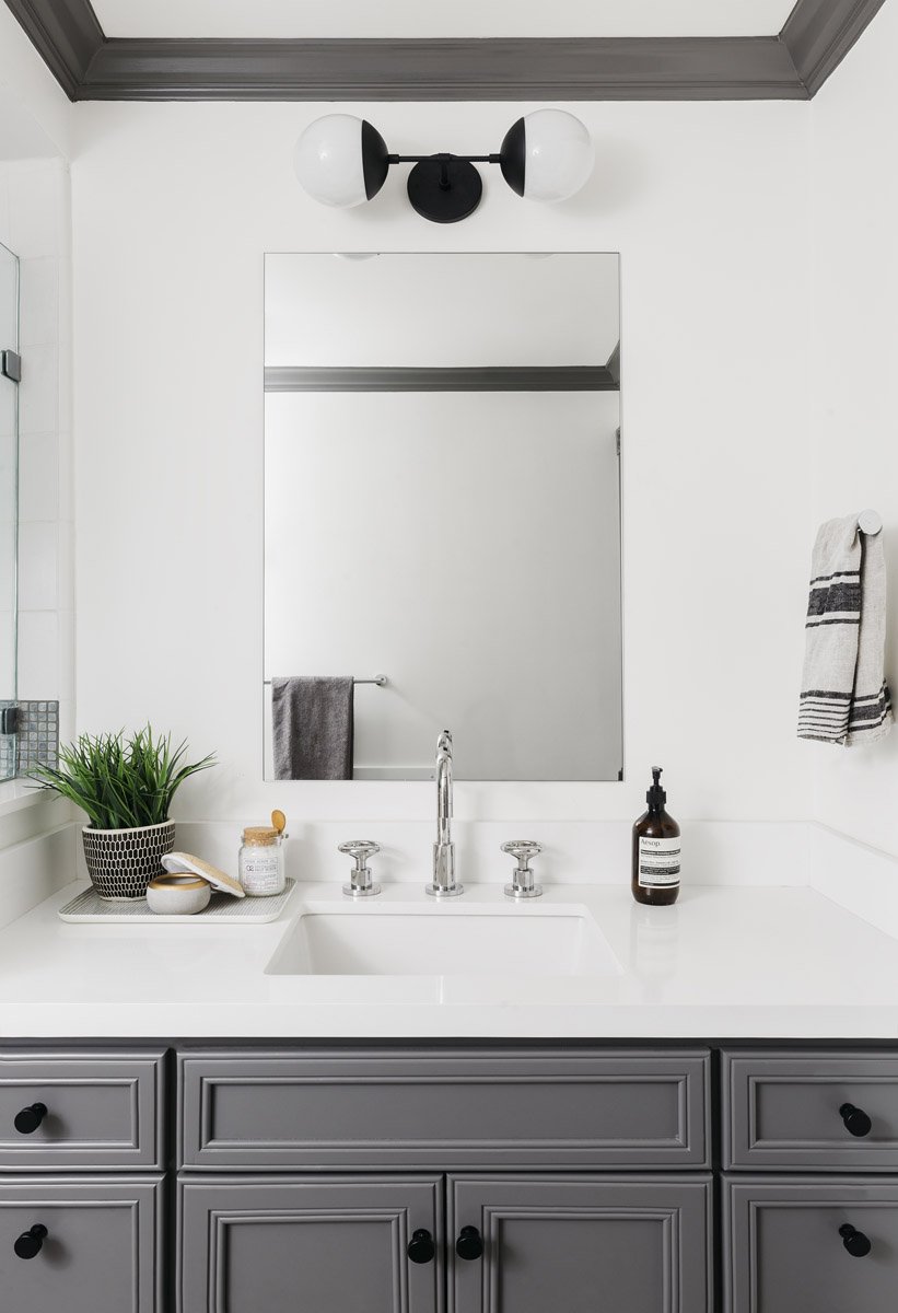 grey bathroom vanity with rectangular mirror and black sconce