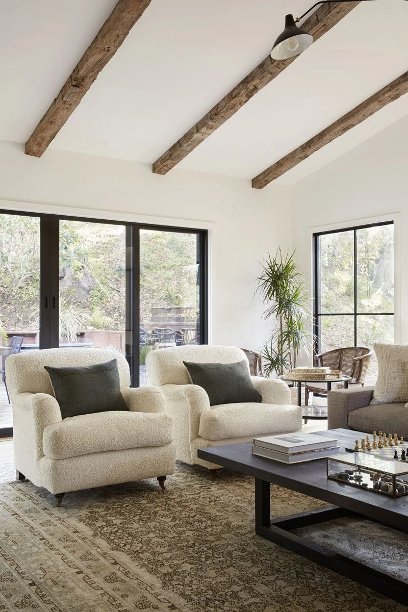cream armchairs and coffee table under exposed ceiling beams