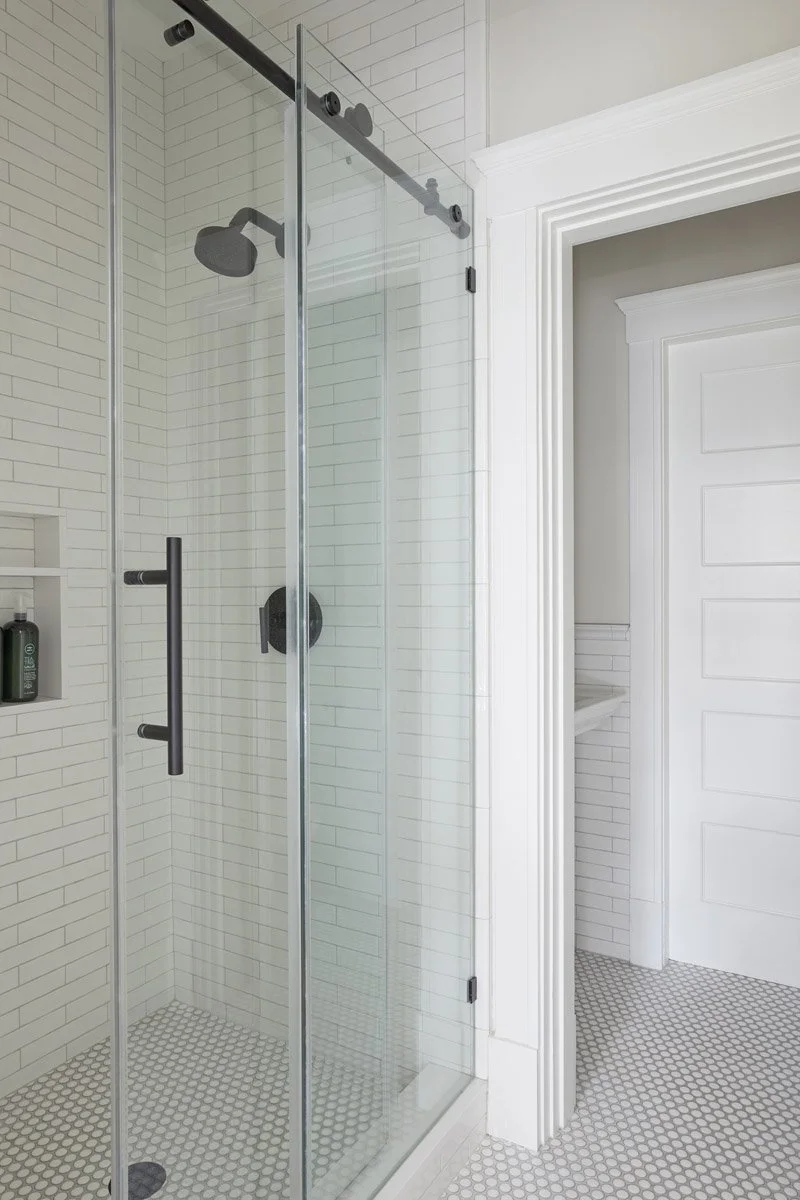 glass walk-in shower with white tile and black hardware