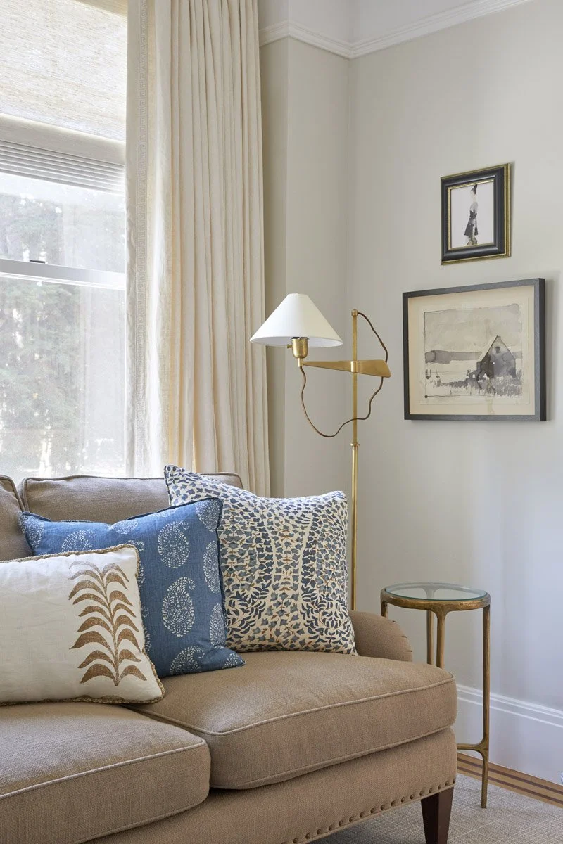 blush sofa with blue patterned pillows beside a brass floor lamp