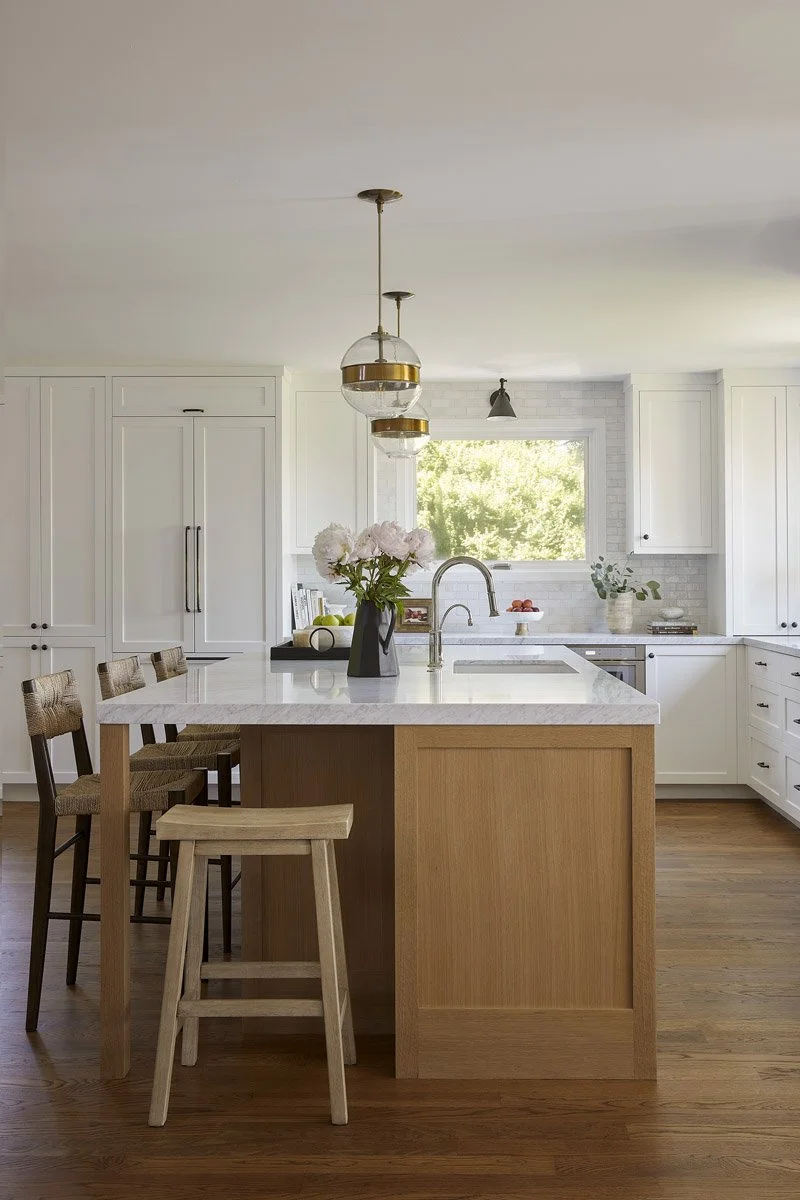 white oak kitchen island with wooden stools and brass pendant lights