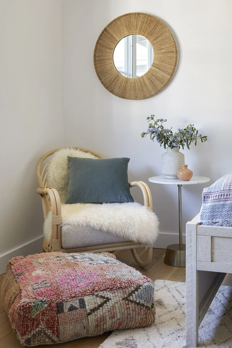 nursery corner with rattan chair, sheepskin throw and kilim pouf