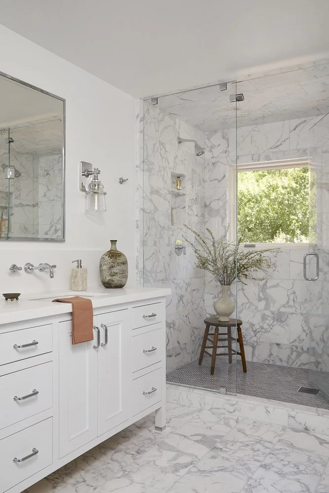 marble bathroom with white vanity and walk-in shower