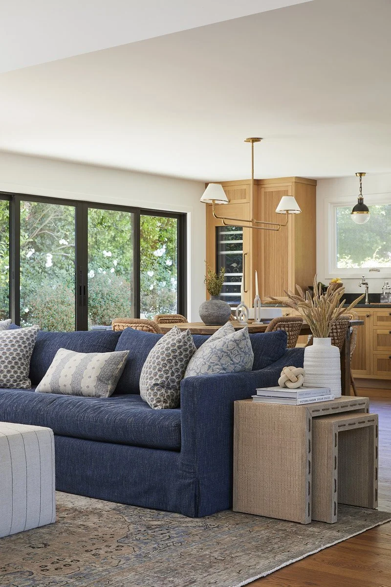 navy sofa with patterned pillows in front of large black-framed windows