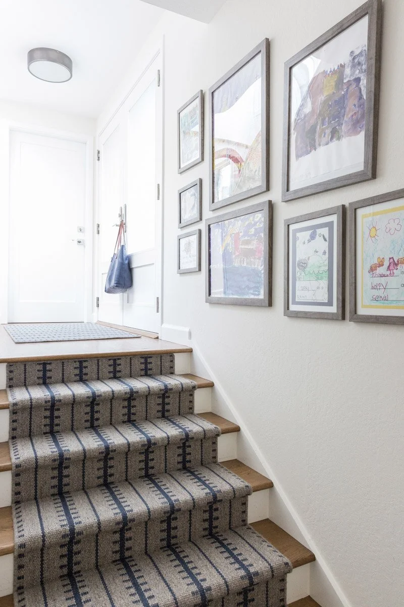 staircase with striped runner and gallery wall of framed art