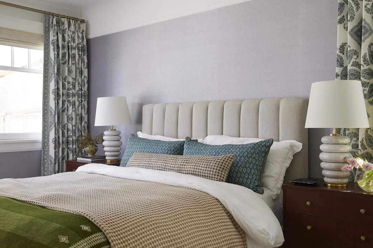 primary bedroom with channelled headboard, green throw and botanical curtains