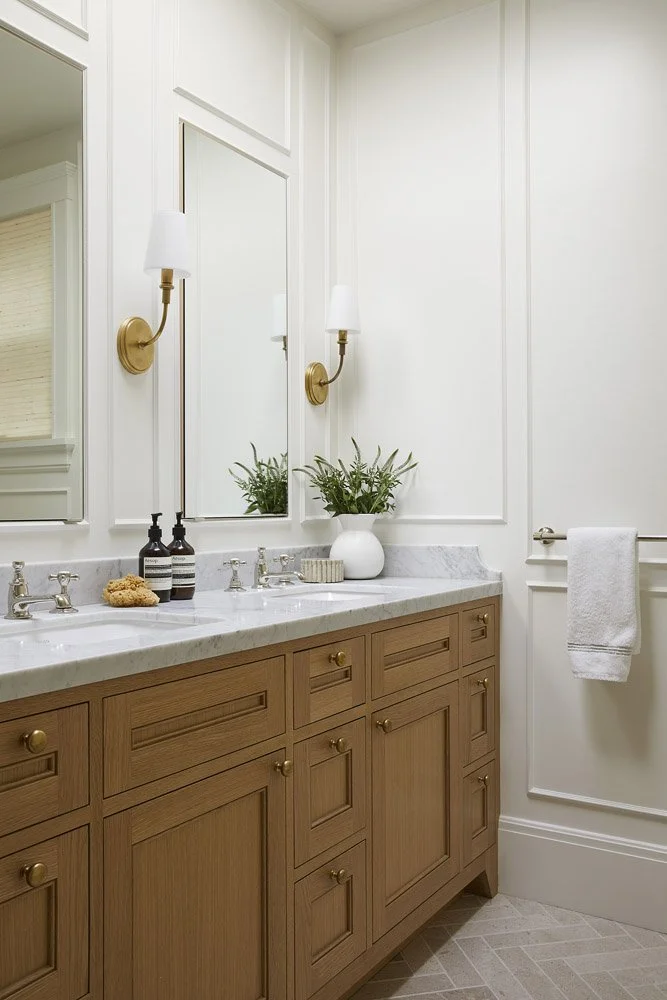 bathroom with wood double vanity, white countertop and brass sconces