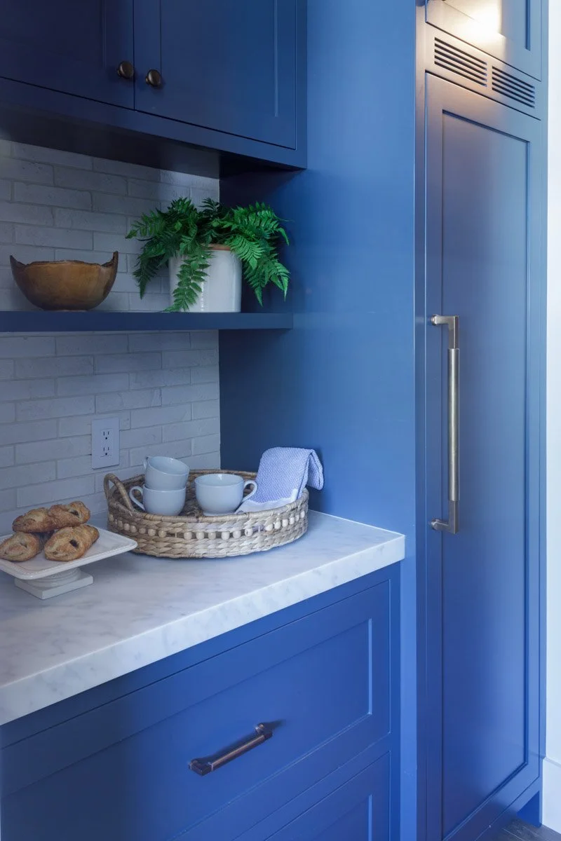 laundry room with bright blue cabinetry, open shelf and marble countertop