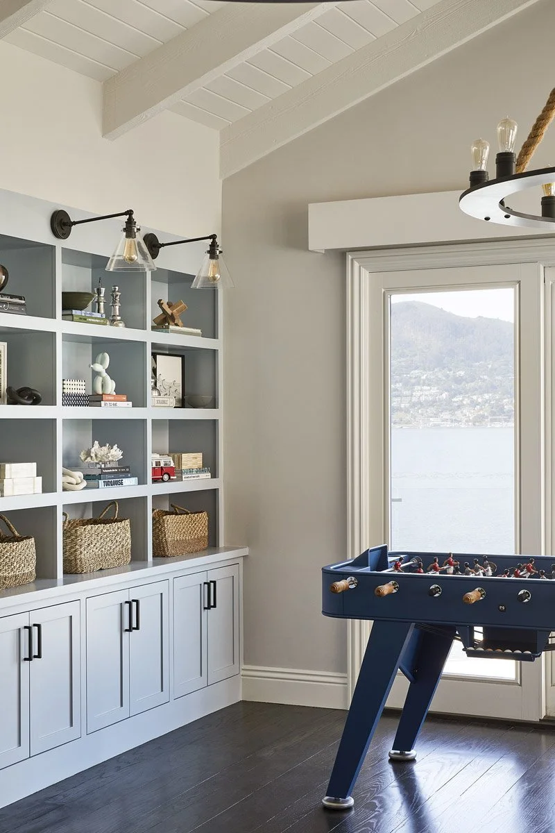 game room with foosball table, built-in shelves and water view through glass door