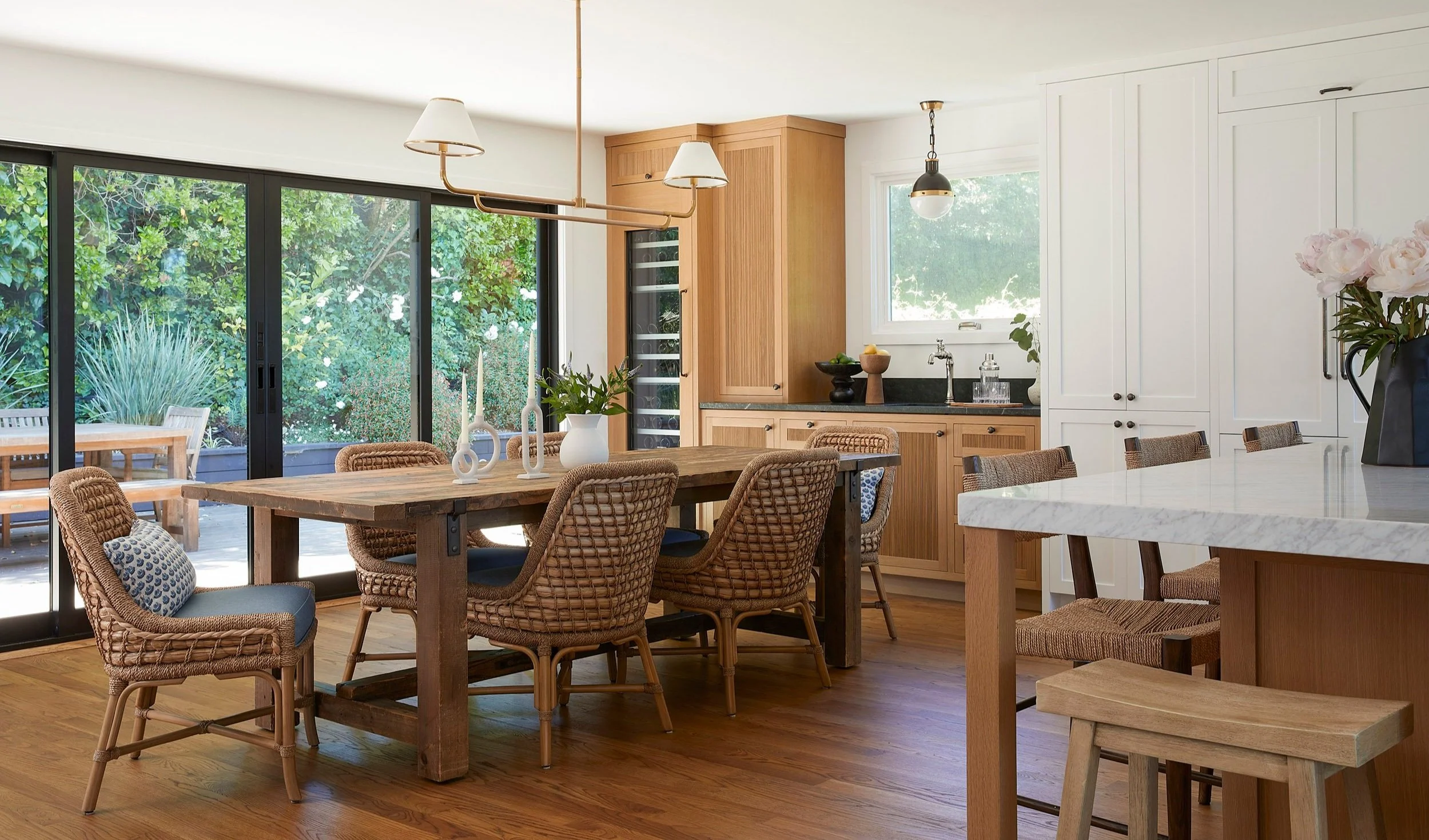 dining area with woven chairs and long wood table beside the kitchen