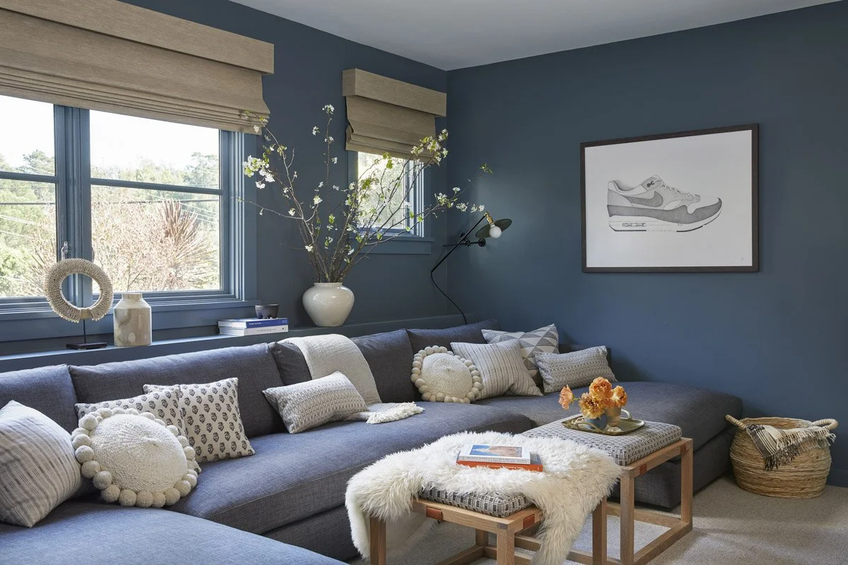 blue family room with sectional sofa, wood coffee tables and woven roman shades