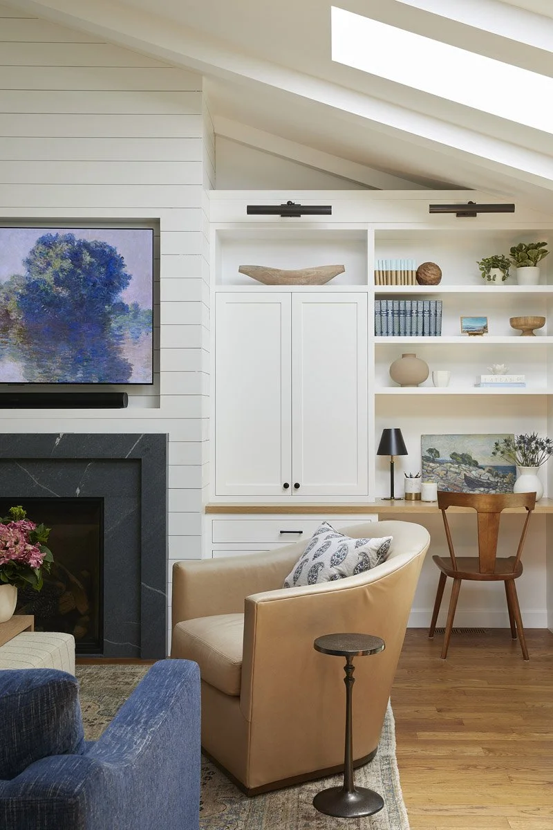 swivel armchair beside the fireplace with built-in cabinets and shelving