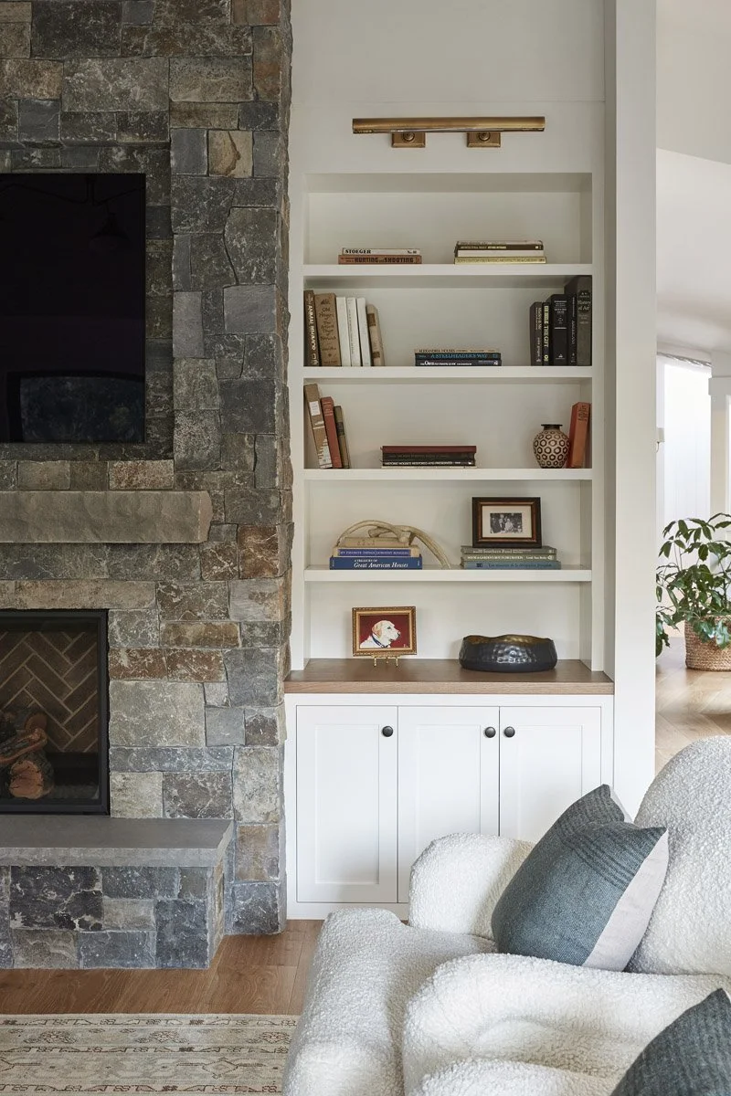 stone fireplace wall beside white built-in shelves with wood countertop
