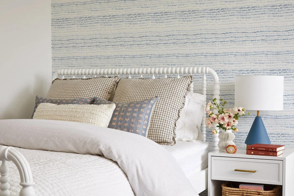 bedroom with textured blue wallpaper, white spindle bed and blue ceramic lamp