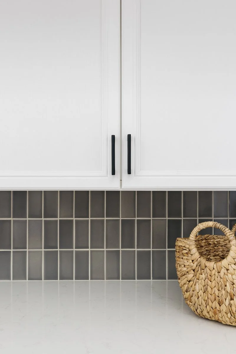 laundry area with white cabinets and grey tile backsplash