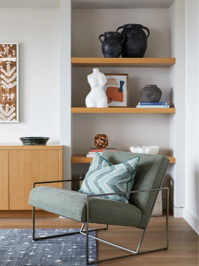 green leather lounge chair beside built-in wood shelving