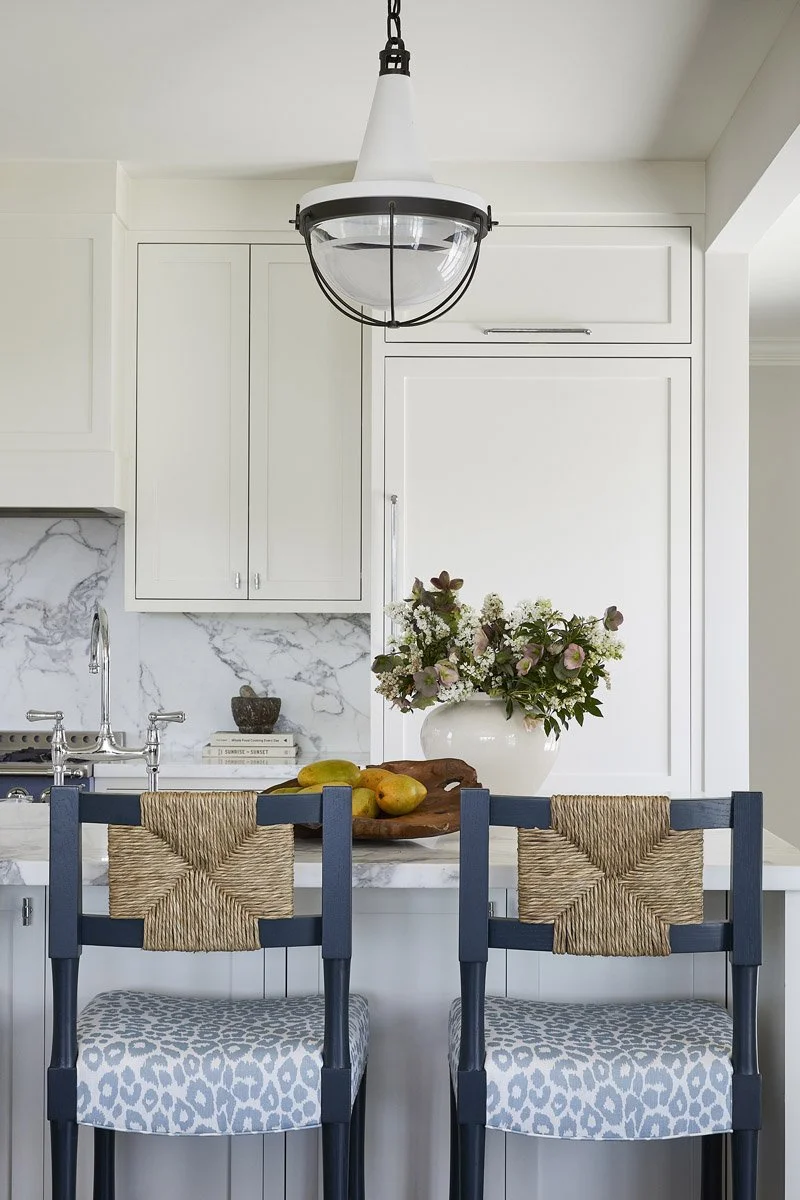 kitchen island with blue counter stools and a glass pendant light