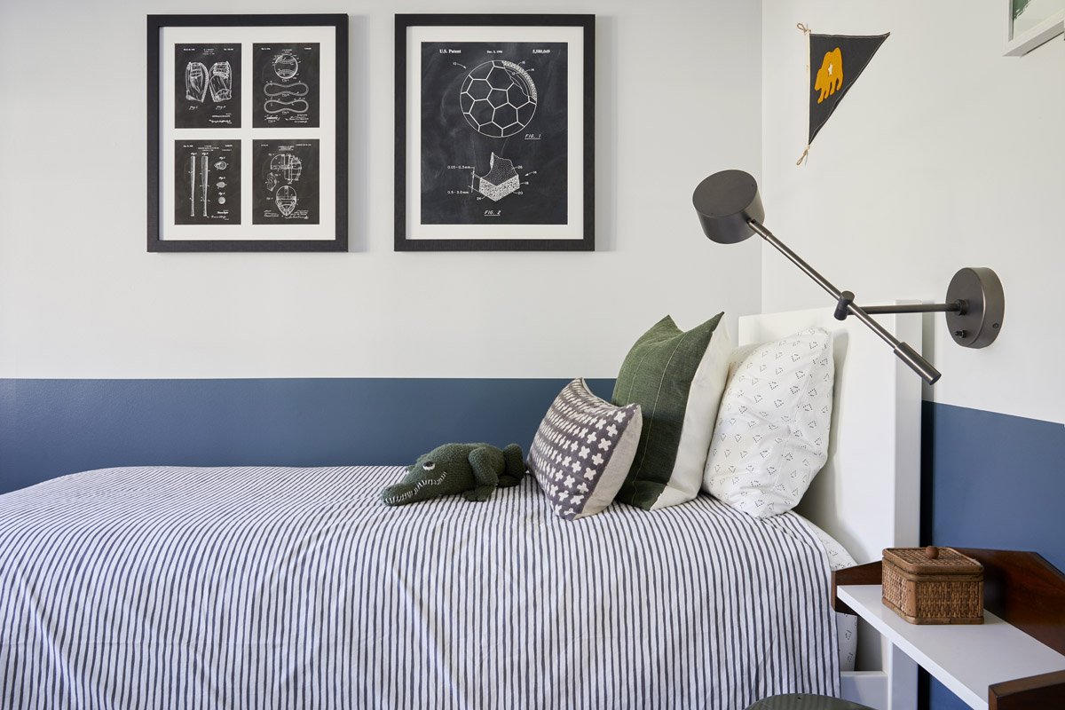 boys bedroom with striped bedding, blue painted wall stripe and framed prints