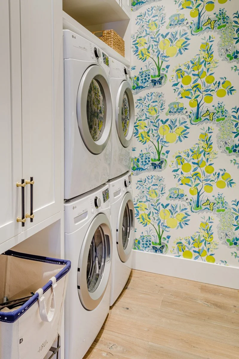 laundry room with stacked washer and dryer and lemon print wallpaper