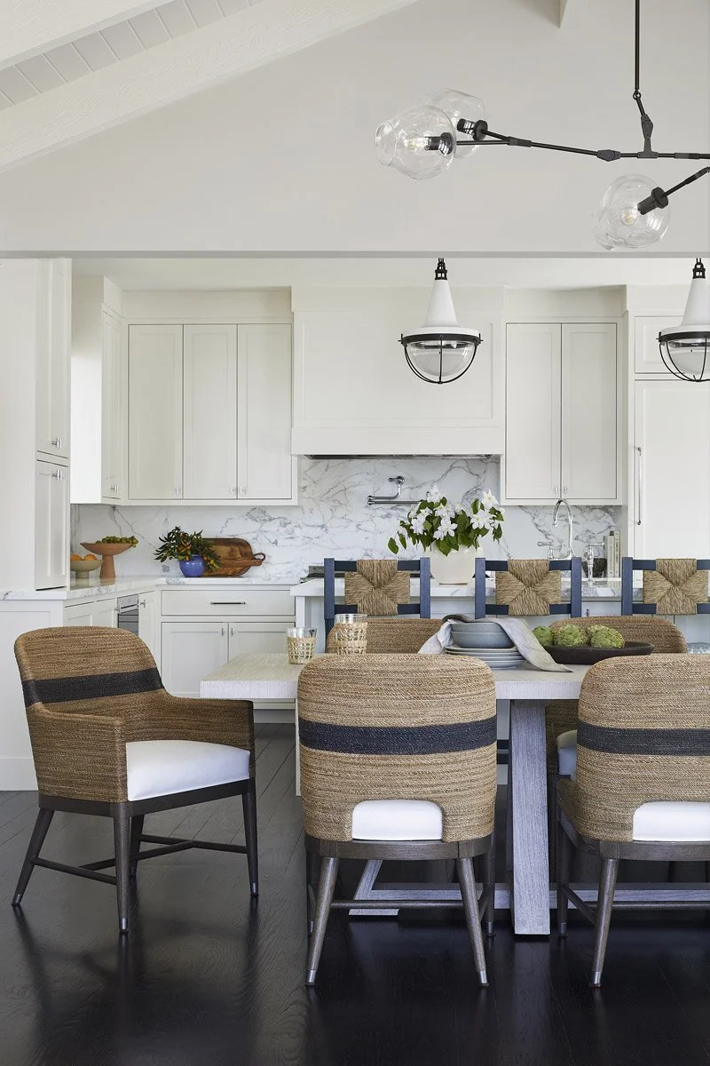 dining room looking into a white kitchen with black pendant lights