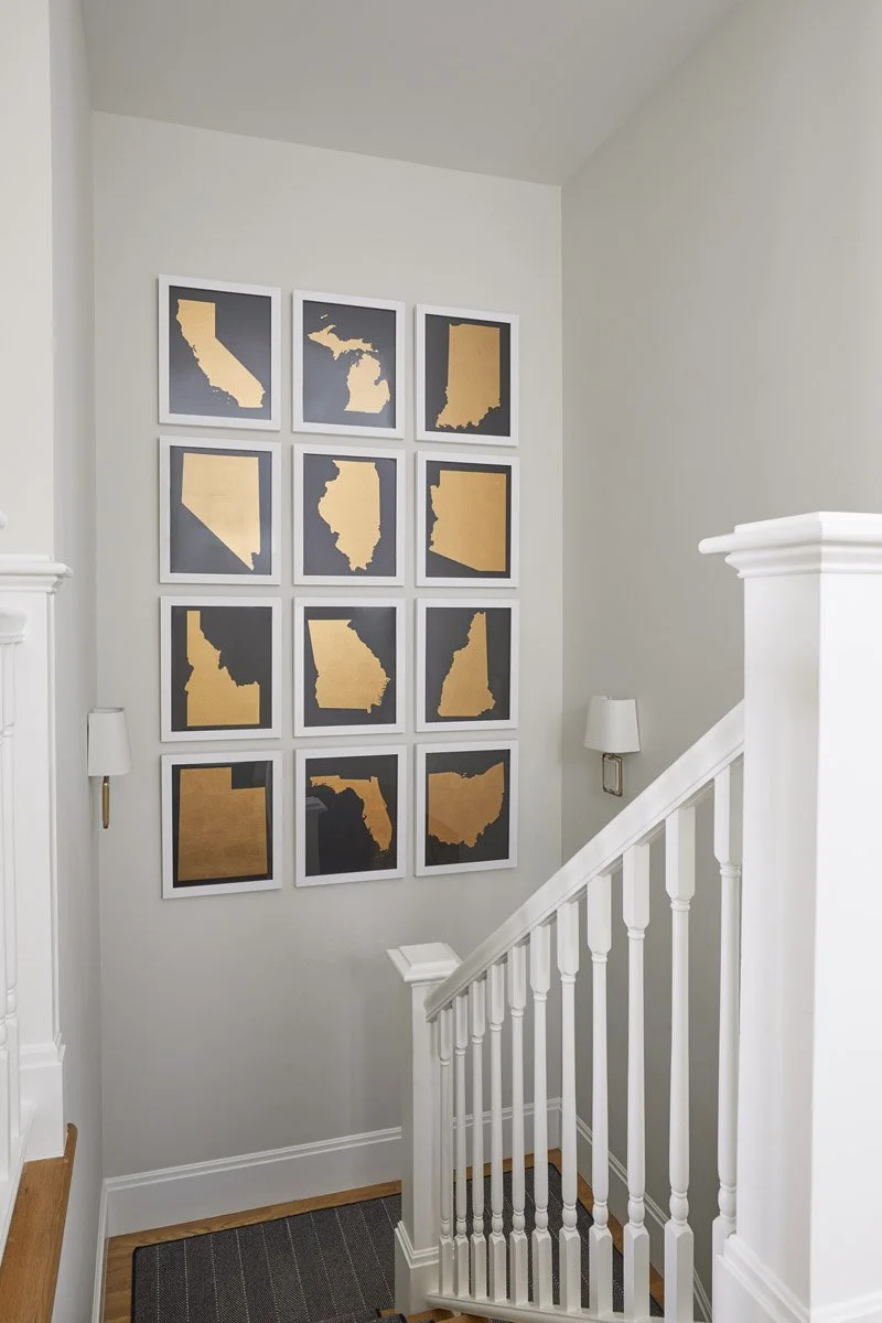 staircase landing with white balustrade and grid of framed map prints