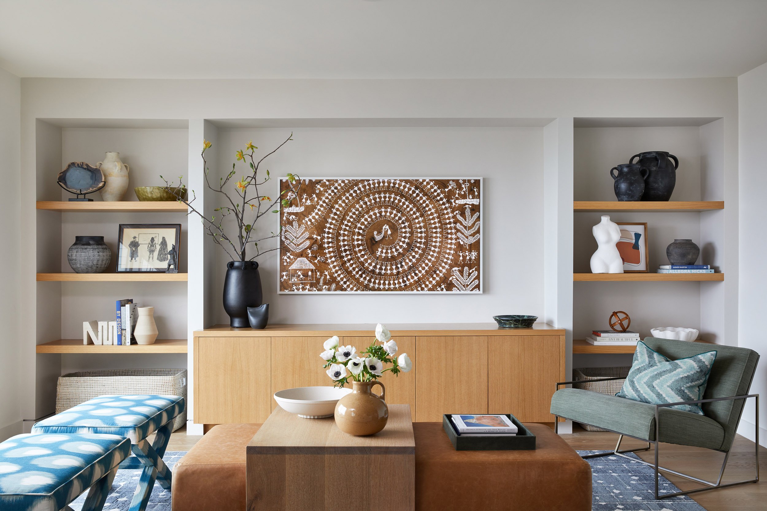 living room with built-in oak shelving, framed textile art and blue upholstered bench