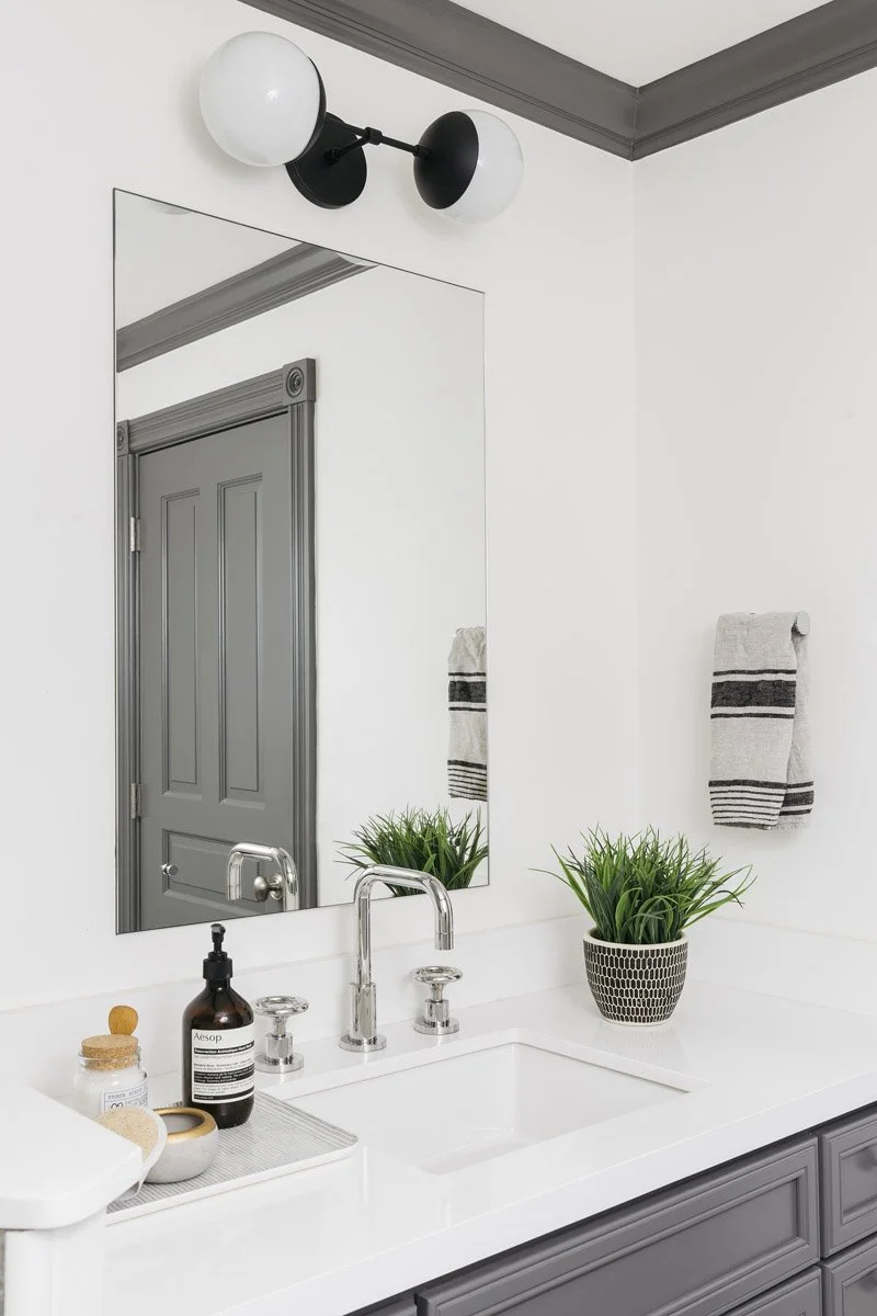 bathroom with grey vanity, white countertop and black wall sconce