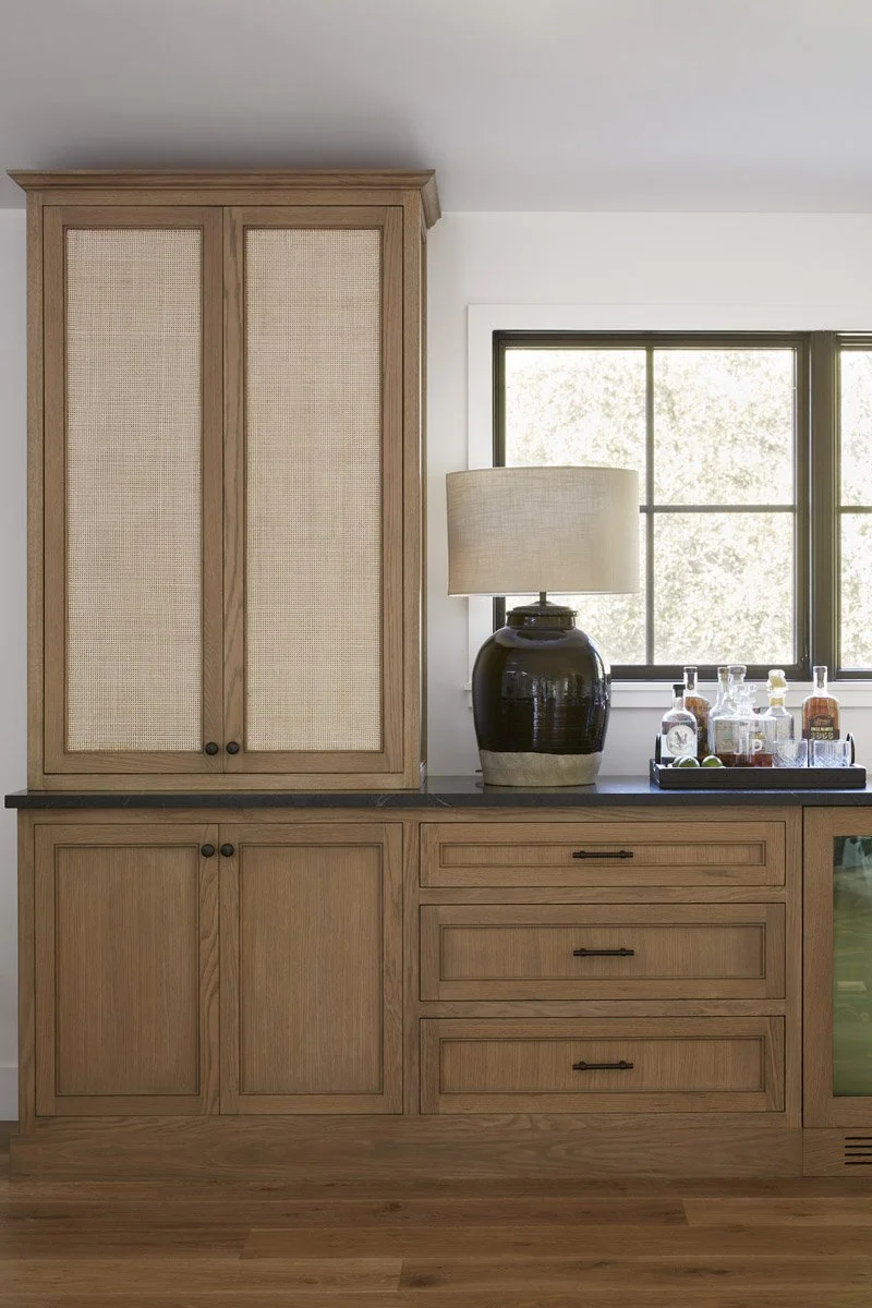 white oak cabinetry with cane panel doors and a black table lamp