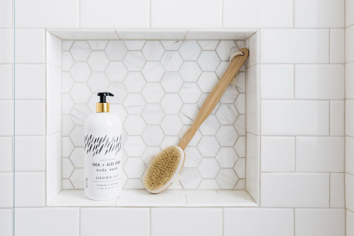 shower niche with white hexagon tile and wooden bath brush