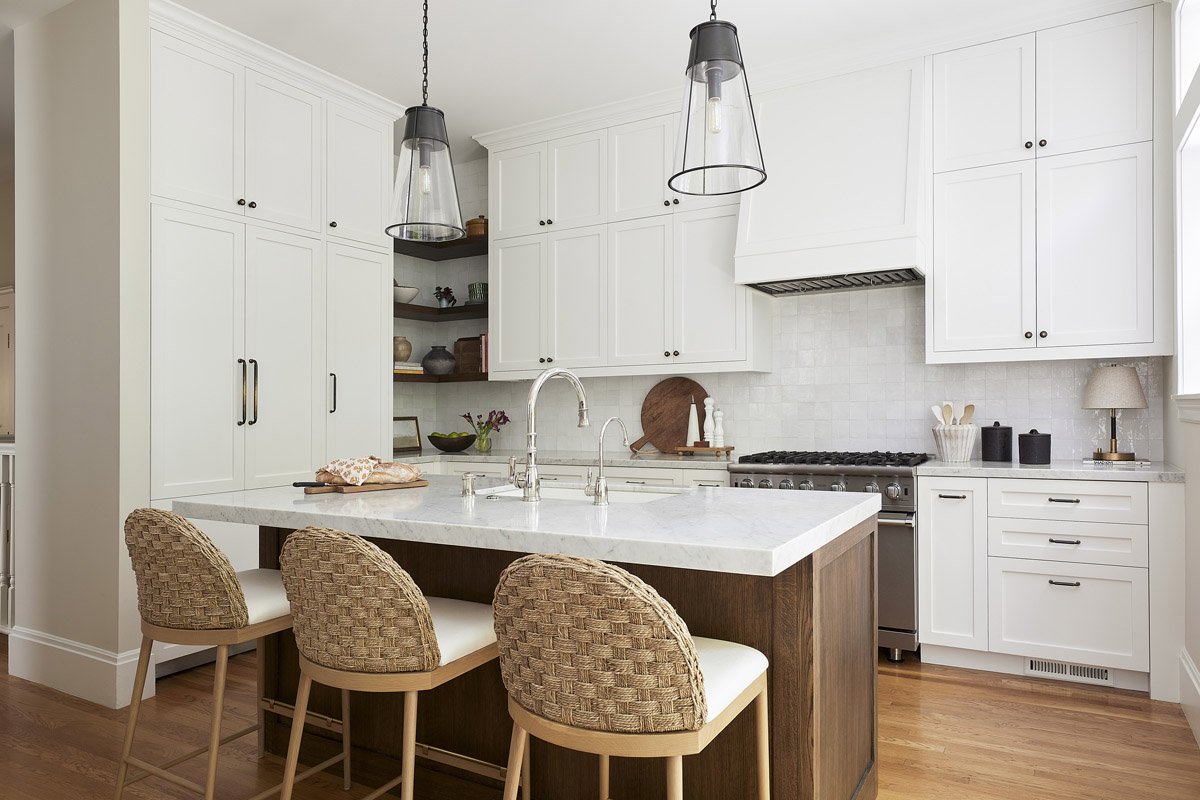 white kitchen with dark wood island and rattan counter stools