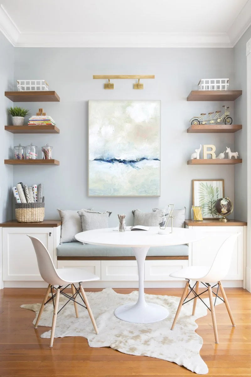 breakfast nook with white tulip table, floating shelves and abstract art