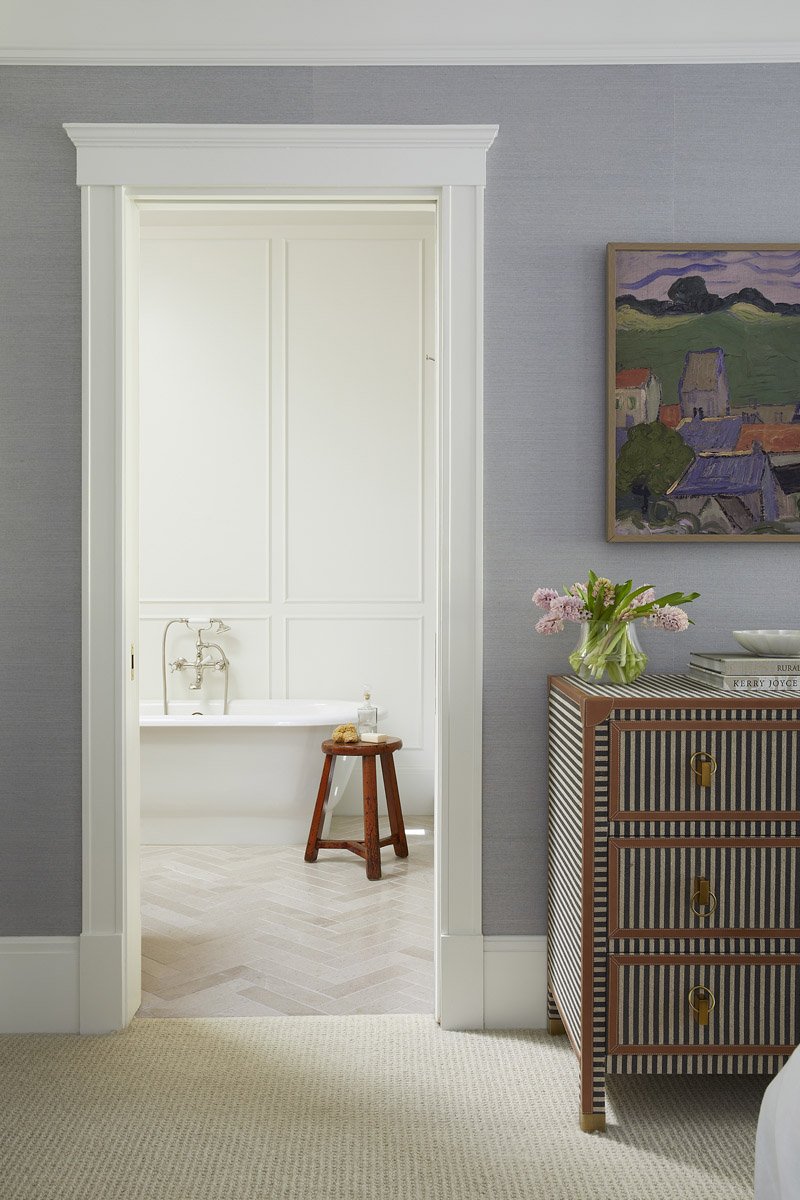 doorway into a primary bathroom with freestanding tub and wooden stool
