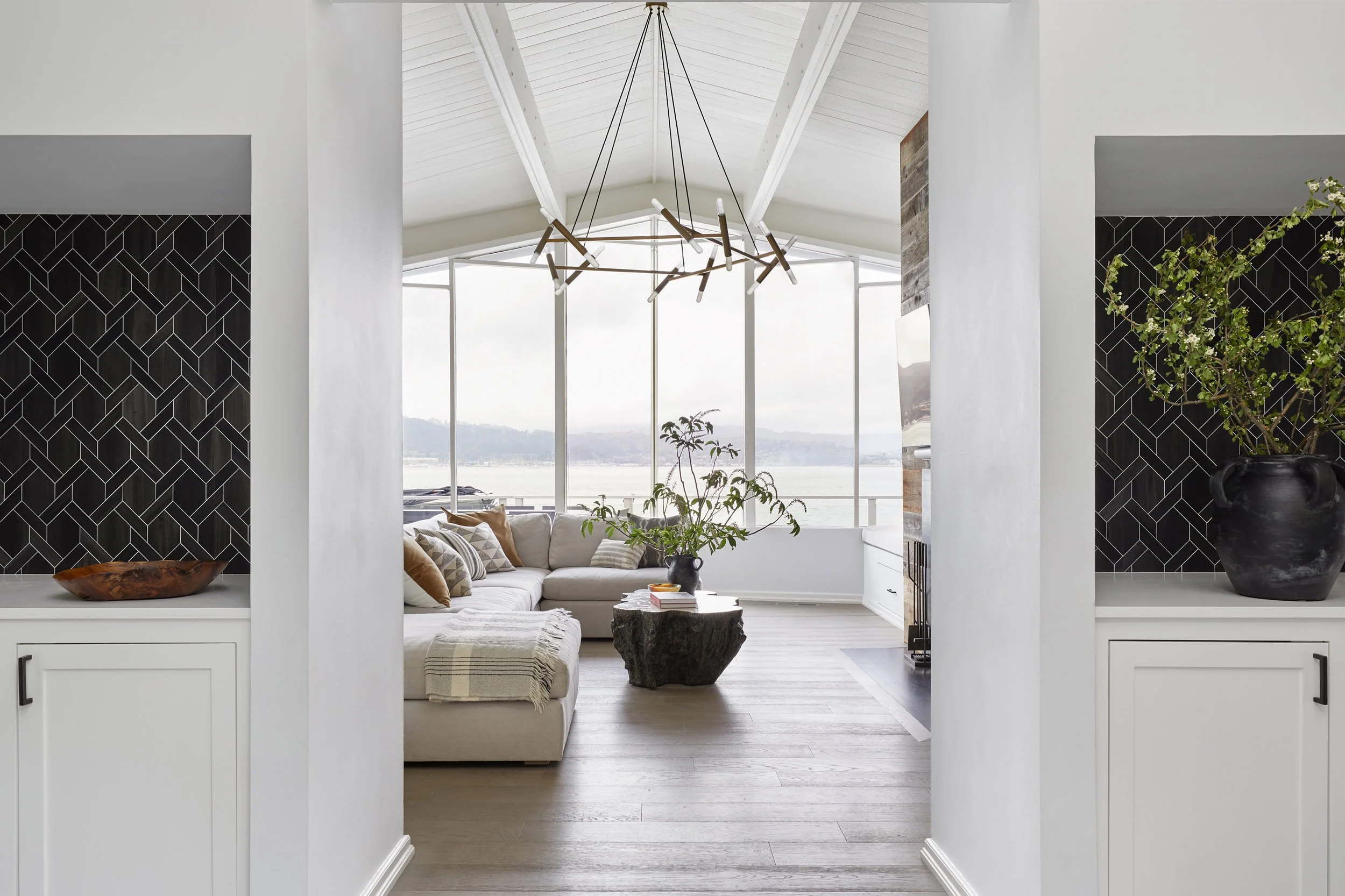 view through a hallway into a waterfront living room with a sculptural chandelier