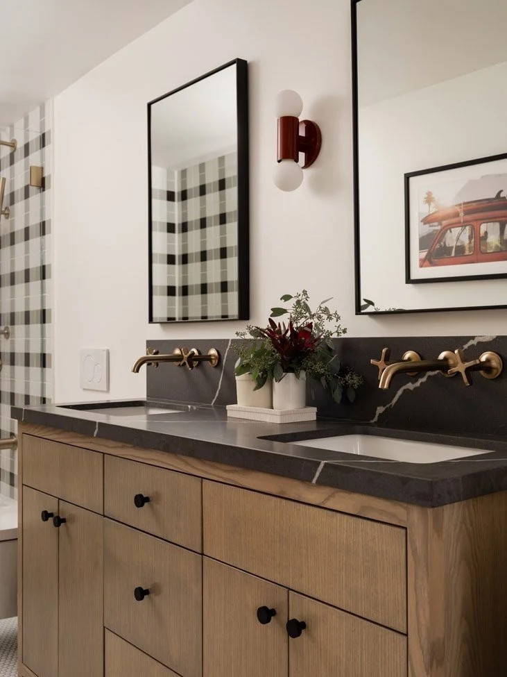 bathroom with wood vanity, black countertop and framed checked artwork