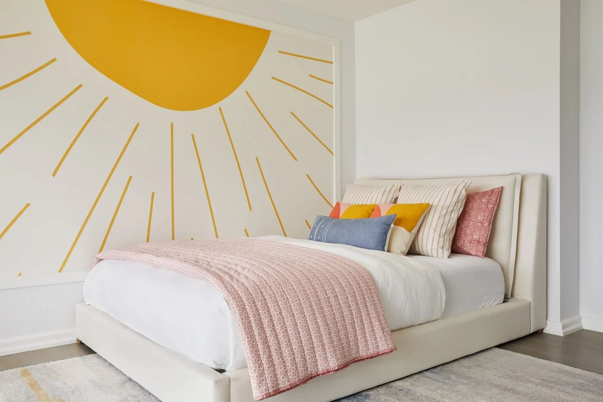 girls bedroom with painted yellow sunburst mural and pink bedding