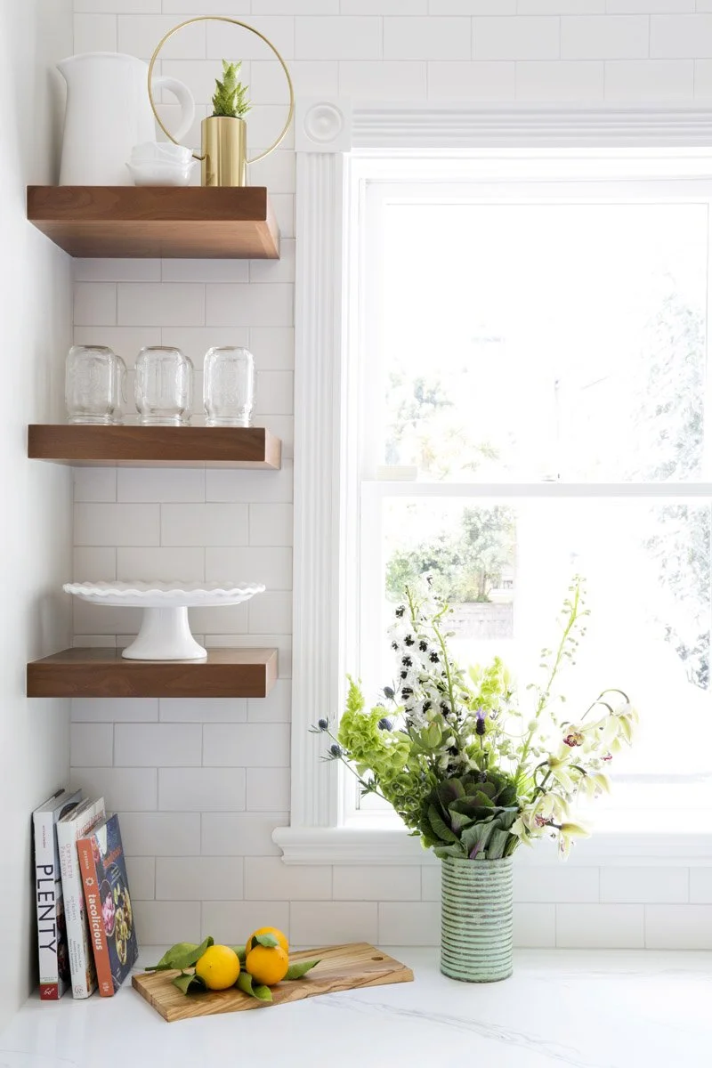 corner floating shelves styled with books, plants and dishes