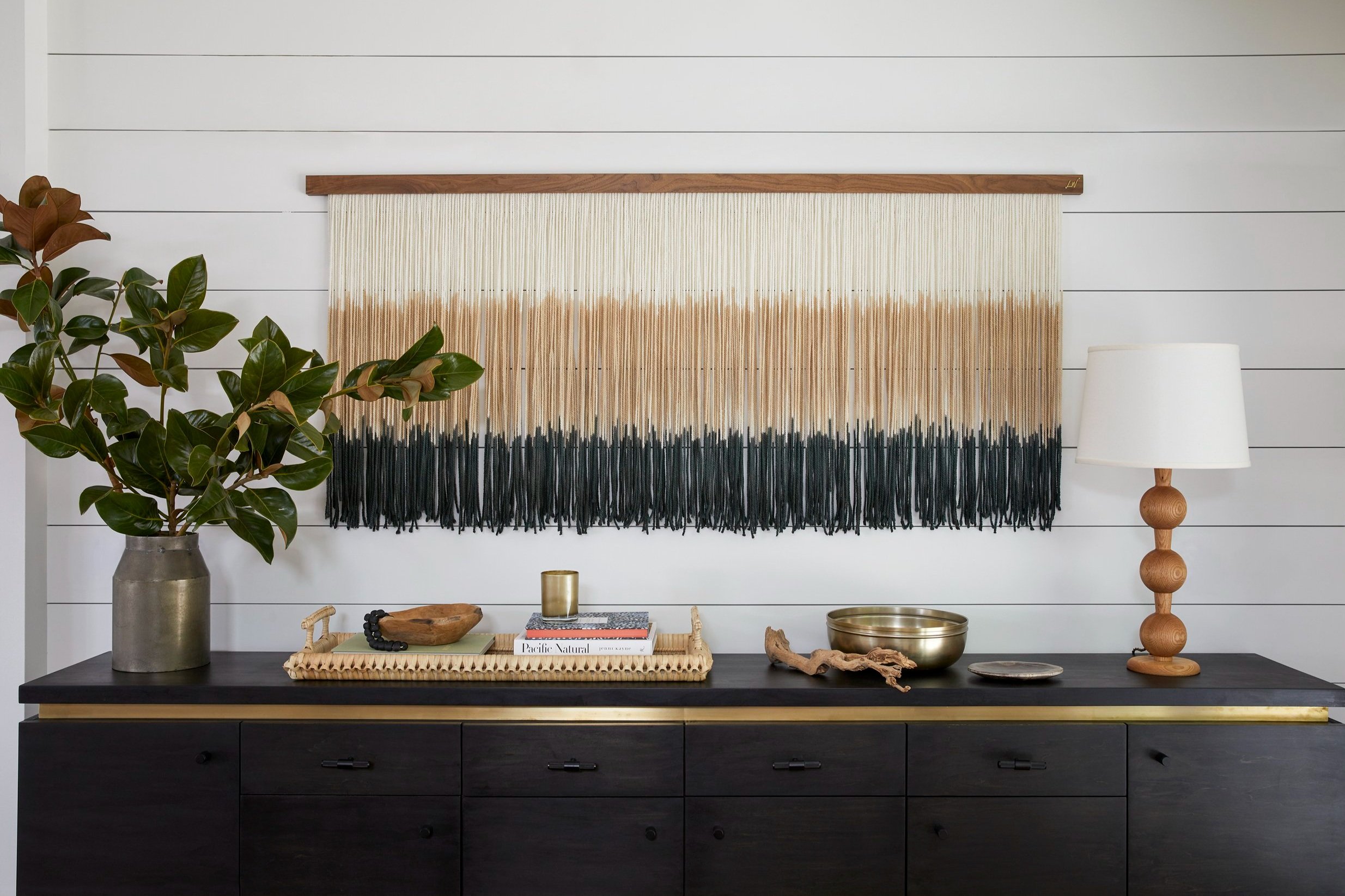 black sideboard with dip-dyed fibre wall hanging and turned wood lampSidemark Studio interior design services guide