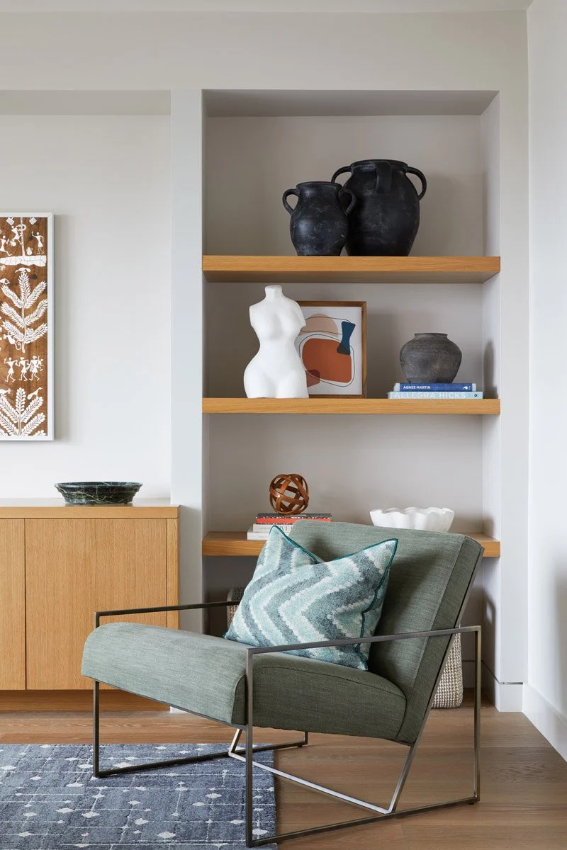 green leather lounge chair beside built-in wood shelving