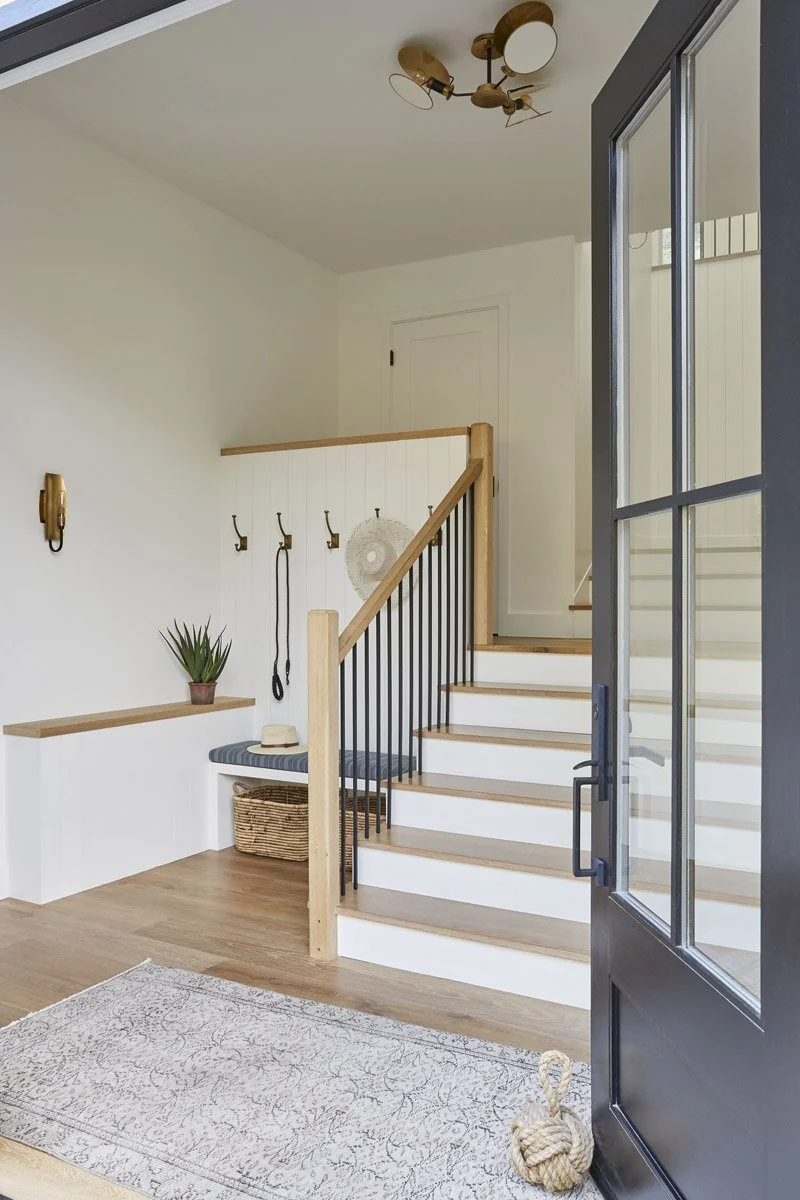 entryway with white staircase, wood treads and black steel glass door