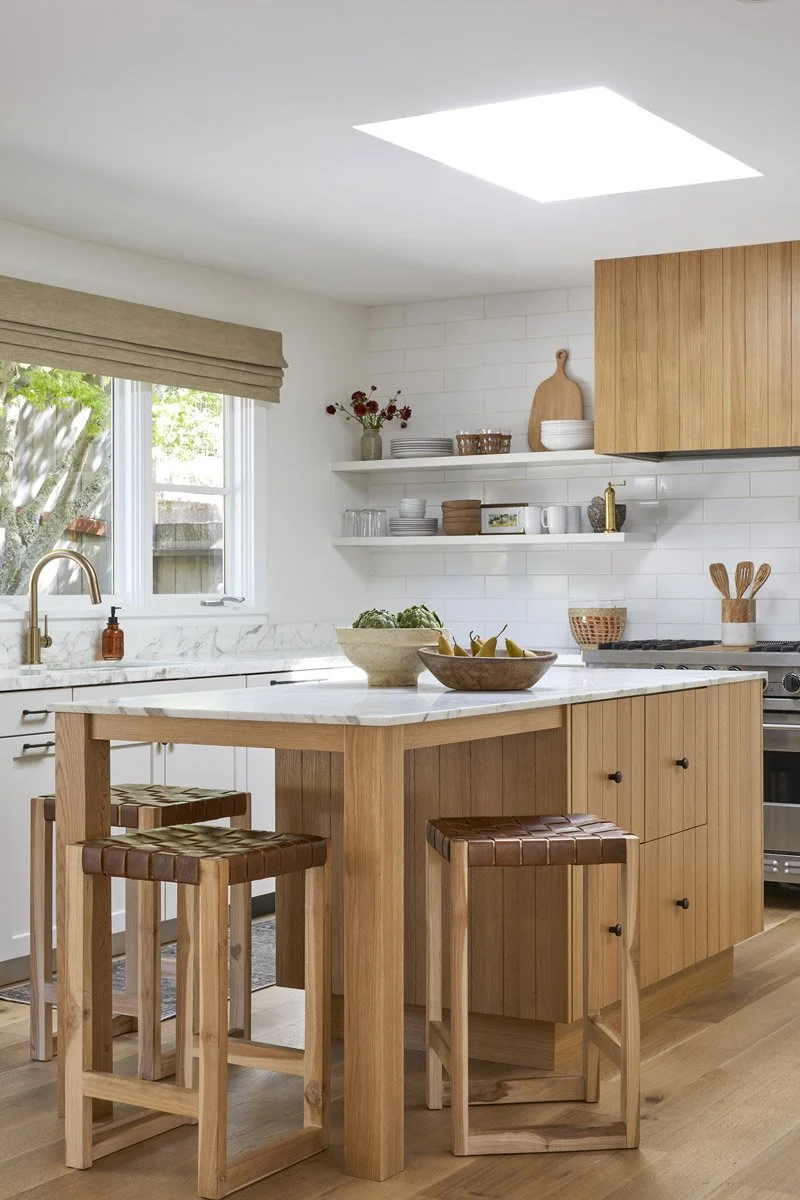 white oak kitchen island with wooden counter stools under a skylight