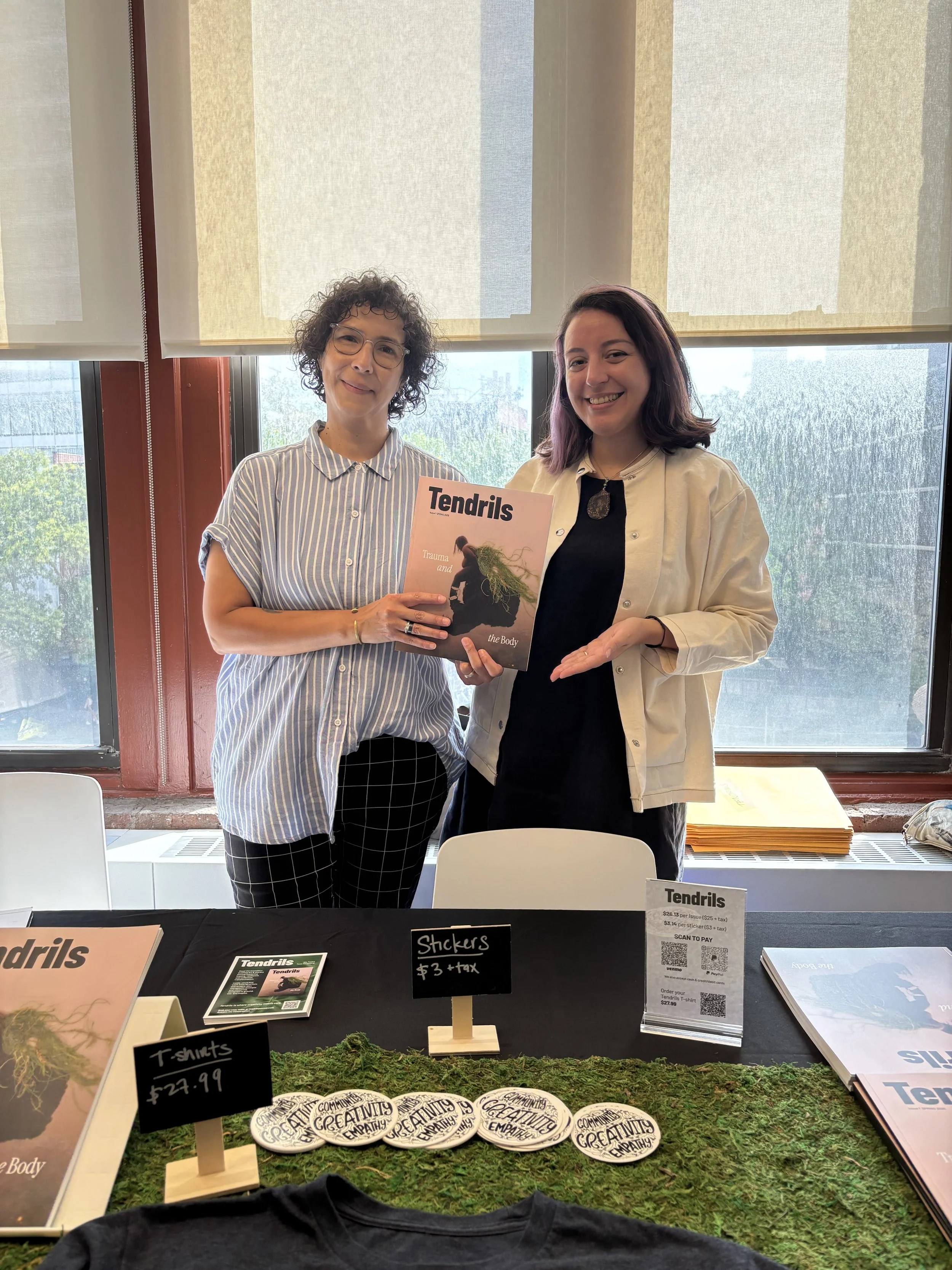 two women holding Tendrils Issue 1 at book fair