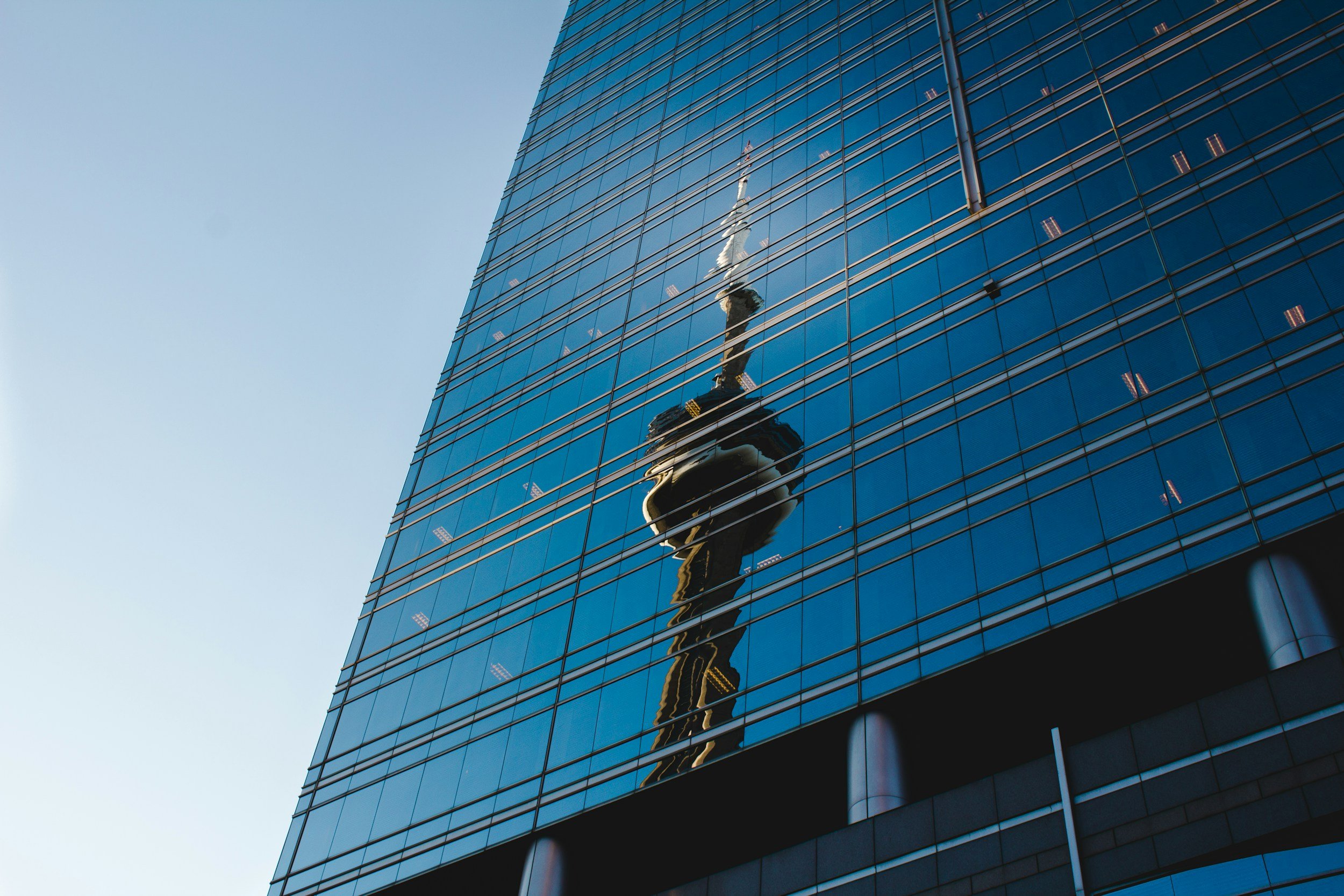 Reflection of the Space Needle captured on the glass facade of a modern skyscraper in downtown Seattle.