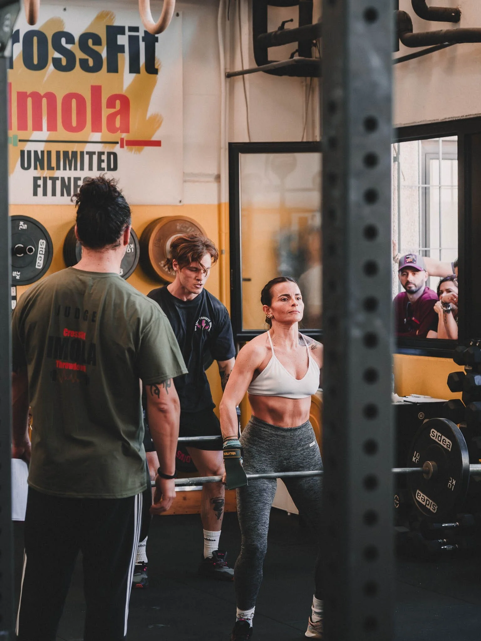 Donna vestita con abbigliamento da palestra che si prepara a sollevare un bilanciere durante un allenamento di CrossFit, in una palestra.