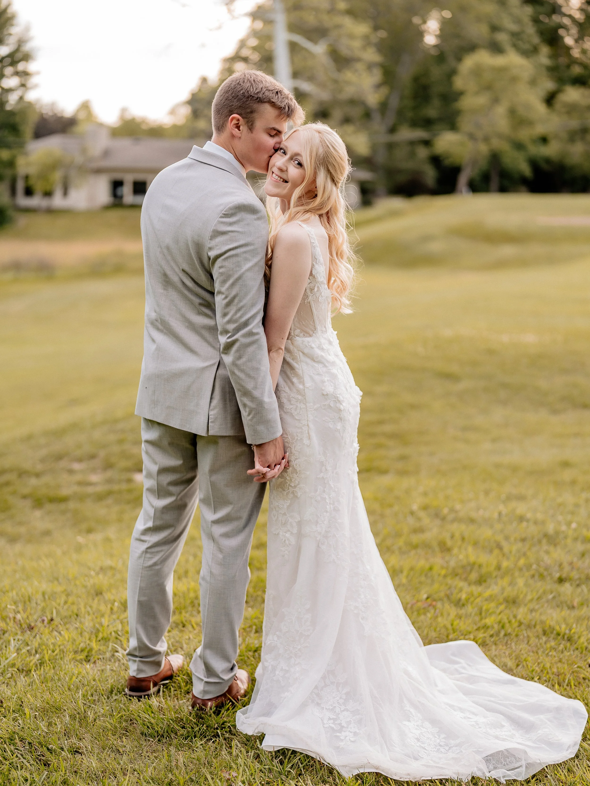 groom kisses bride on the cheek during sunset