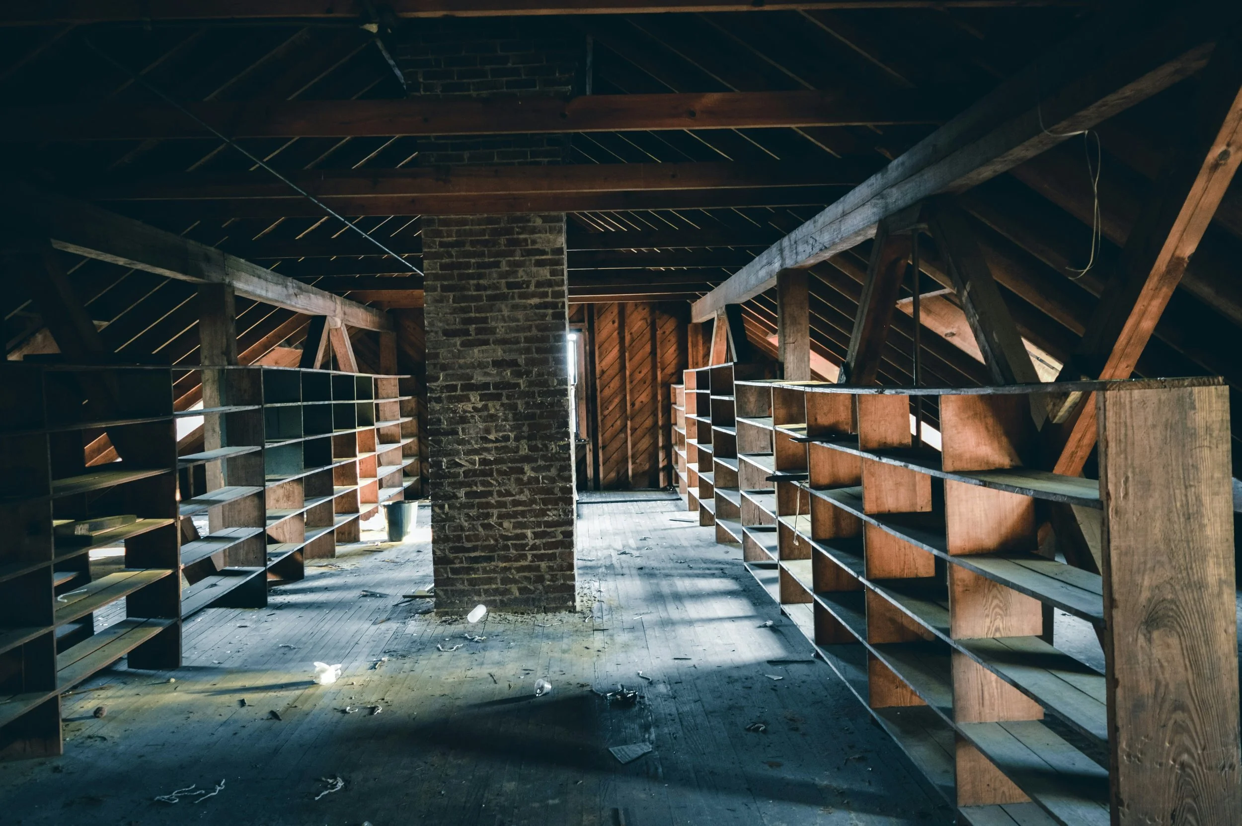 Spacious attic with empty wooden shelves and brick column