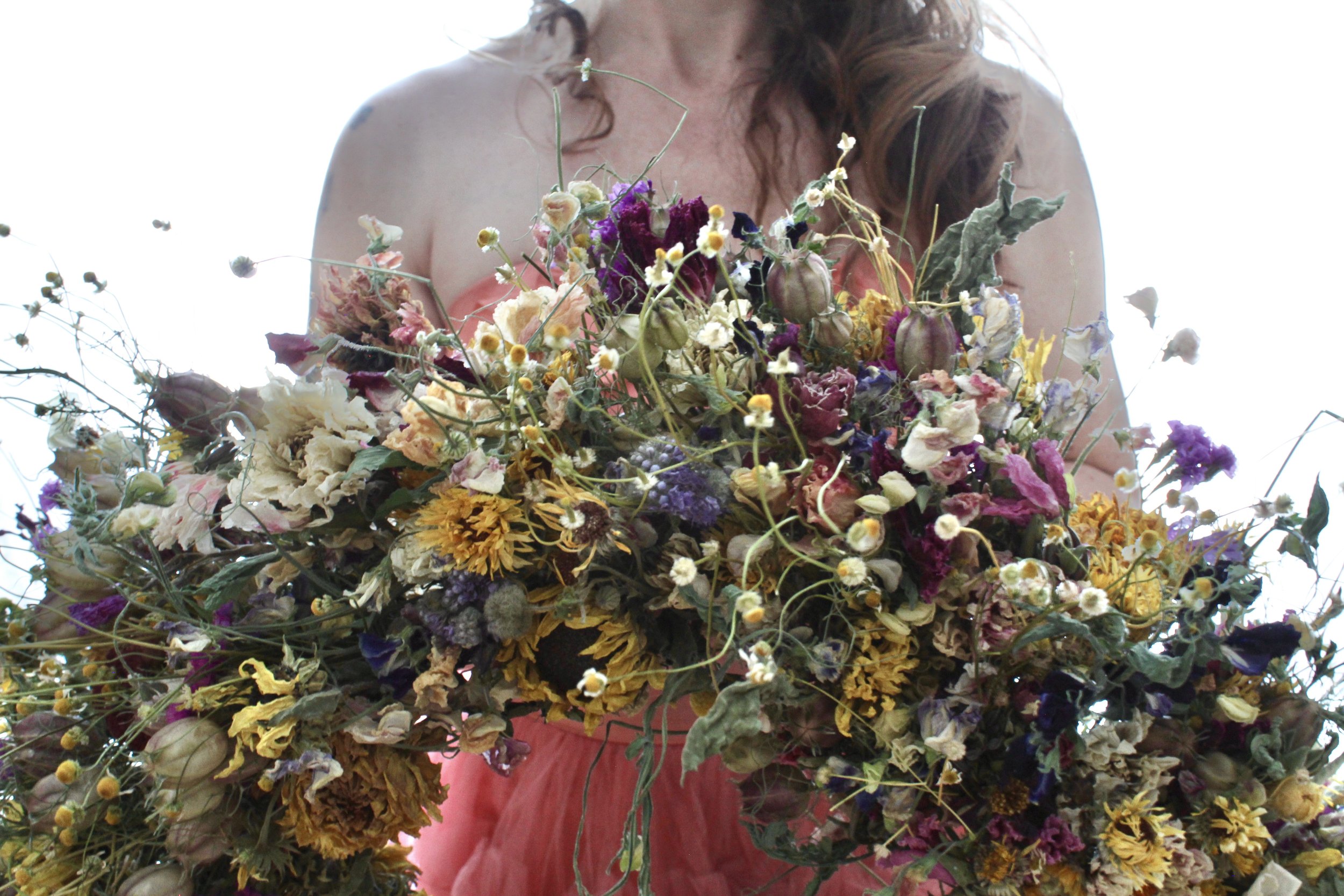 A wreath made from garden-grown dried flowers featuring sunflowers, statice, and German chamomile.