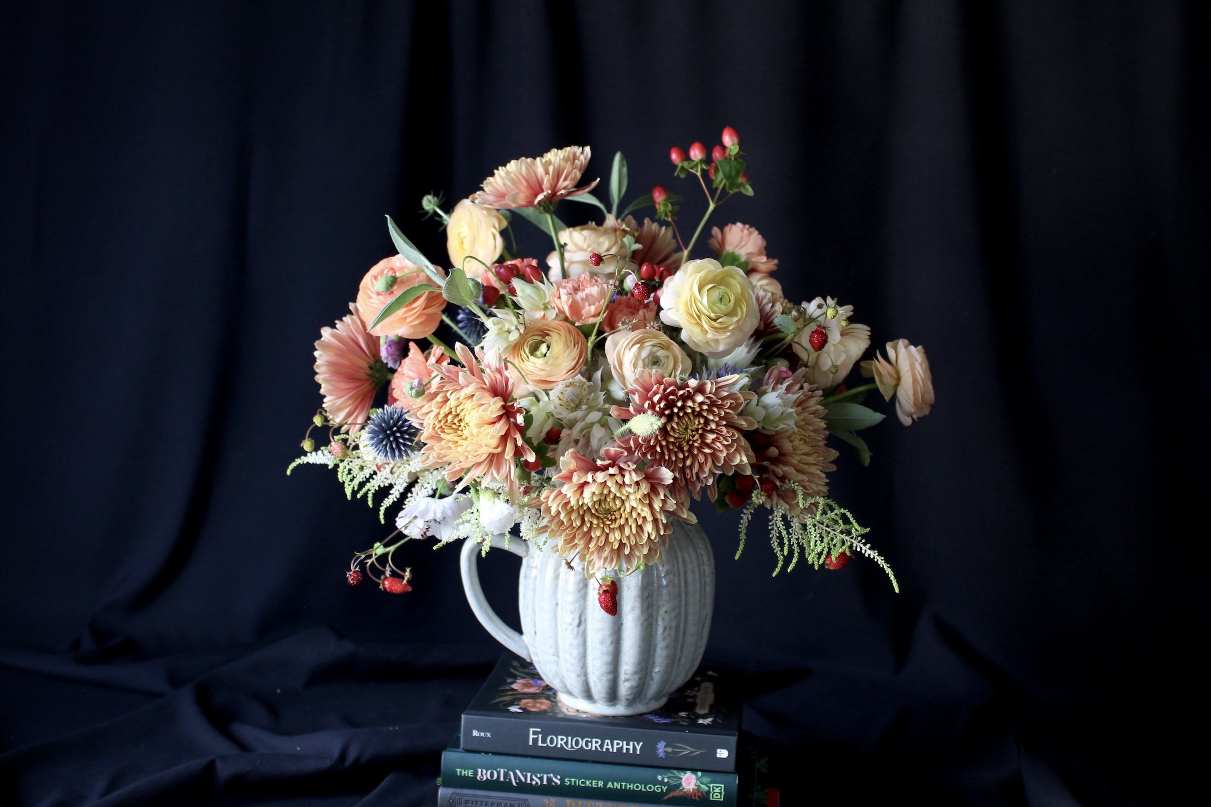 A lush mixed summer arrangement featuring ranunculus, chrysanthemums, sage, and globe thistle.