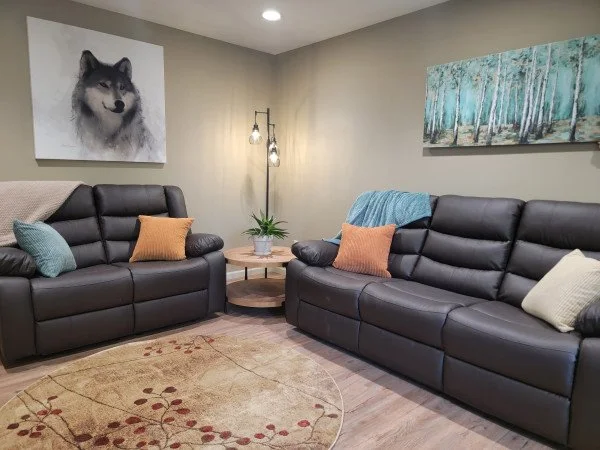 Comfortable vacation rental at Lakeshore Lodging in Homer, Alaska, with plush leather couches, wolf and forest-themed artwork, and cozy lighting—perfect for a relaxing Alaskan getaway.