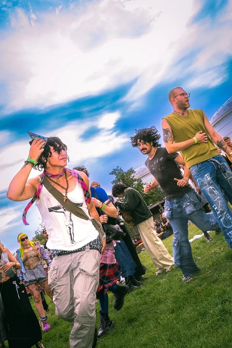 People dancing outdoors under a cloudy sky at a festival or gathering.